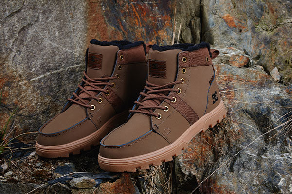 Brown boots with leather details on a rocky surface