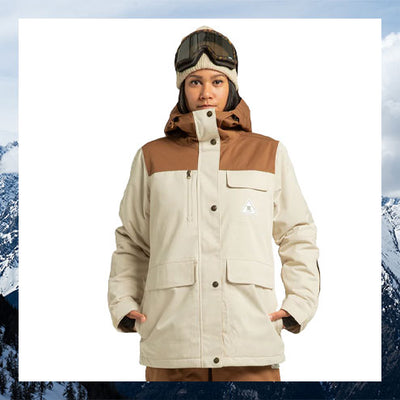 Person wearing a beige and brown snow jacket with goggles on a snowy mountain background